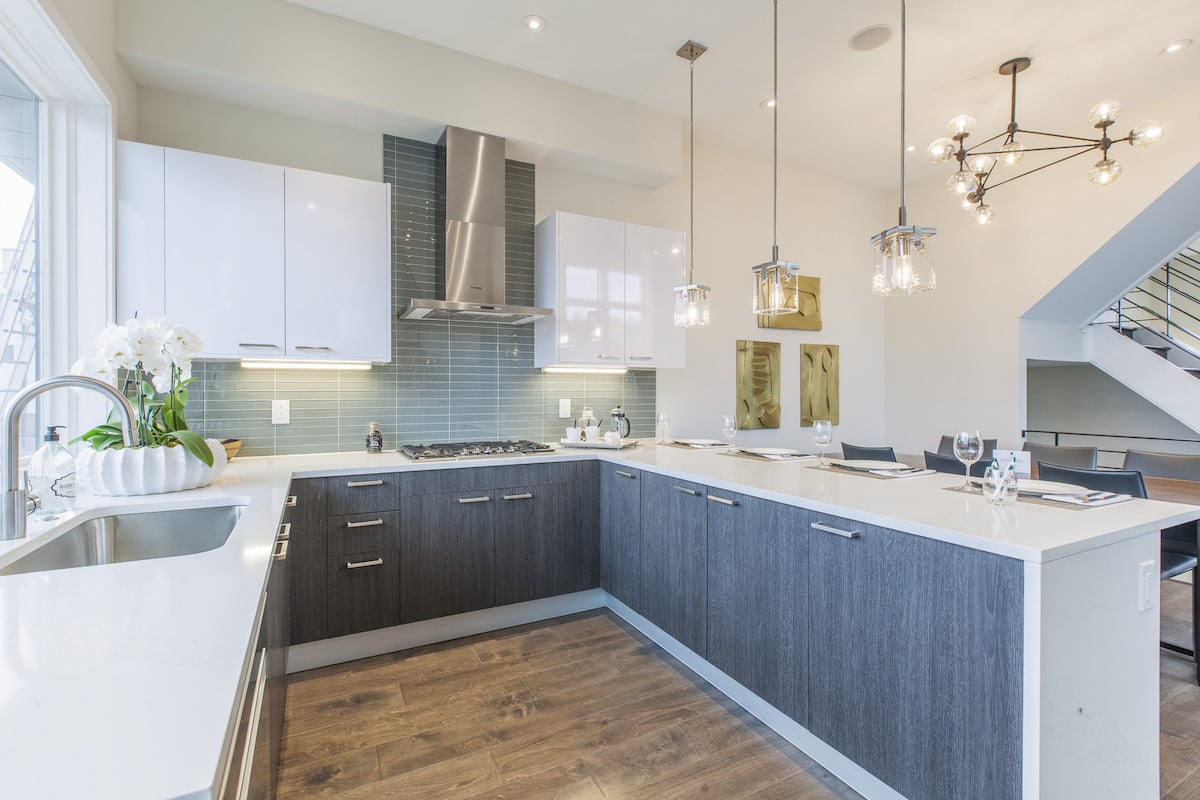 A modern kitchen with hanging lights and white countertops.
